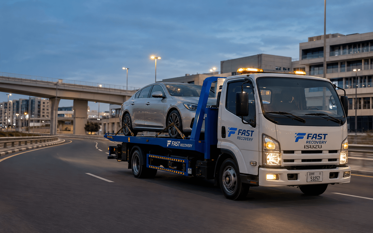 FAST RECOVERY flatbed truck transporting a vehicle through Al Garhoud