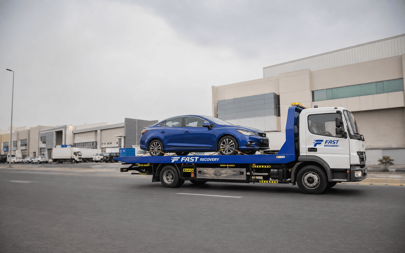 FAST RECOVERY flatbed truck transporting a vehicle through Al Qusais